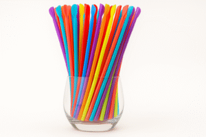 Colorful plastic drink stirrers in a glass vase.